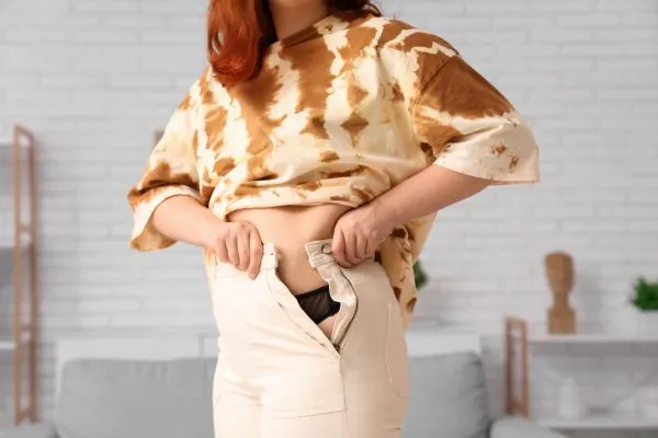 Image of woman trying to do her trousers up after pregnancy weight gain Weston Super Mare