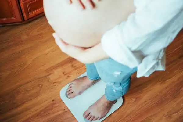 Image of woman weighing herself and experiencing weight gain through pregnancy Weston Super Mare